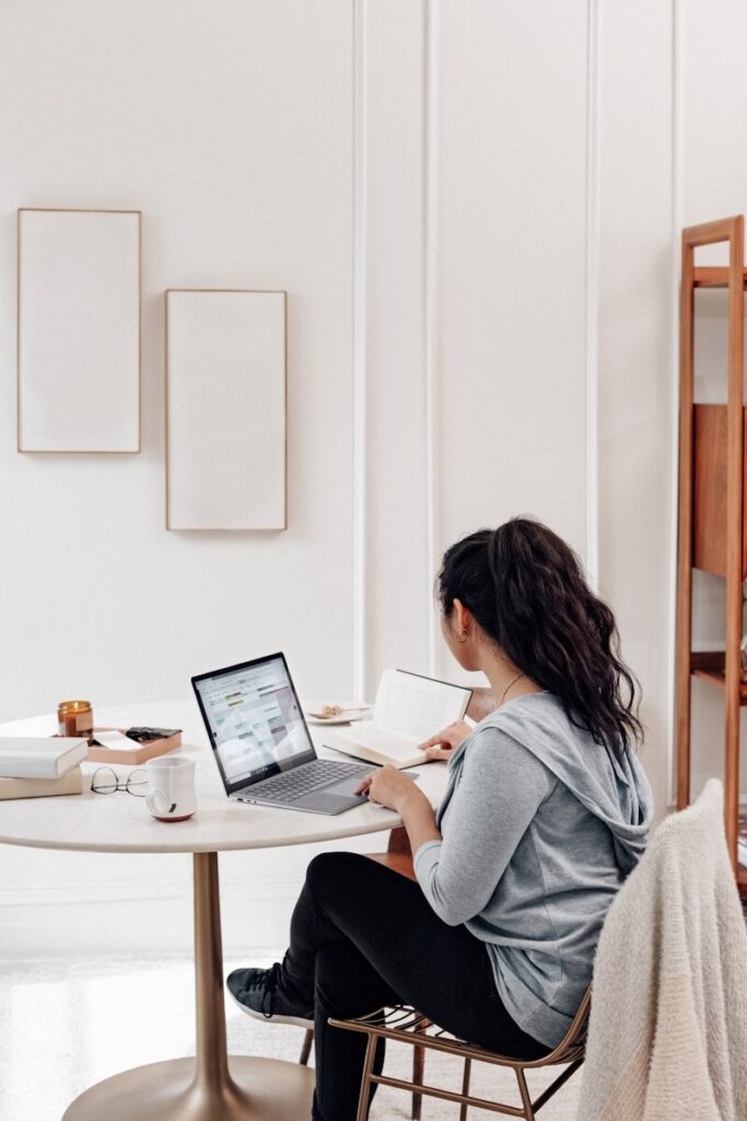 woman in gray sweater using microsoft surface laptop